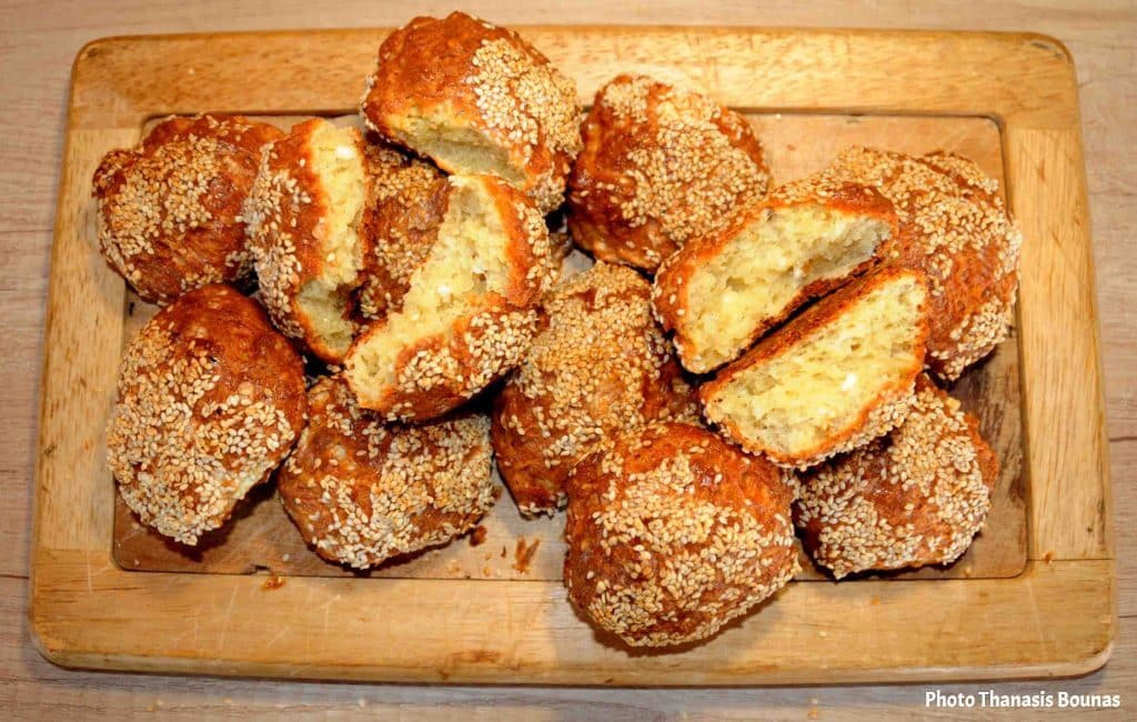 Homemade sesame bread rolls cut in half and served on a wooden cutting board