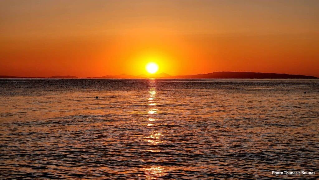 Sunrise over the sea in Greece viewed from a sailboat with calm waters and golden reflections