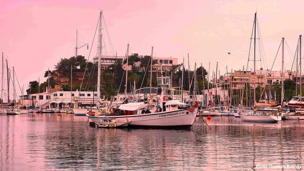 harbor at sunset with sailboats reflecting on calm water