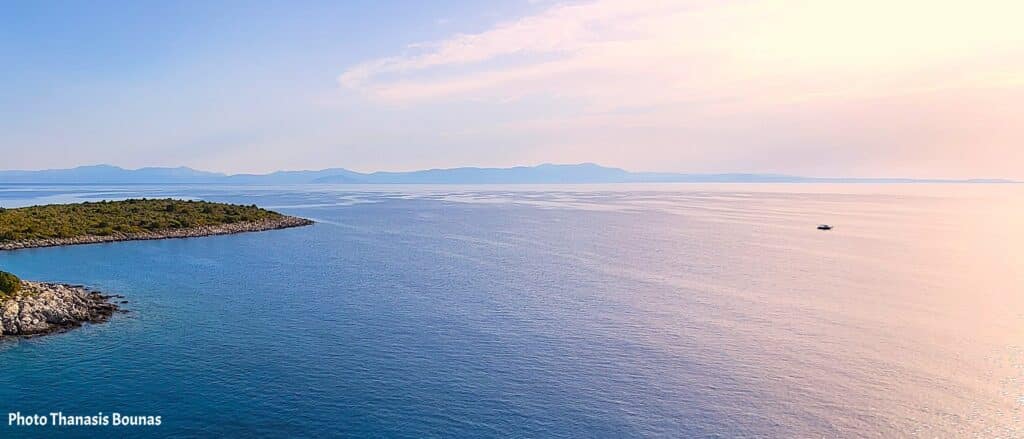 View from above of the sea in Greece with coastline and sailboat distance horizon
