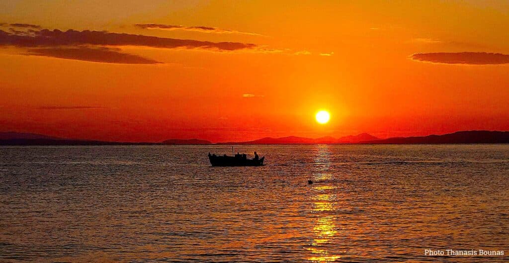 Sailboat at sunset in Greece with orange sky and calm sea