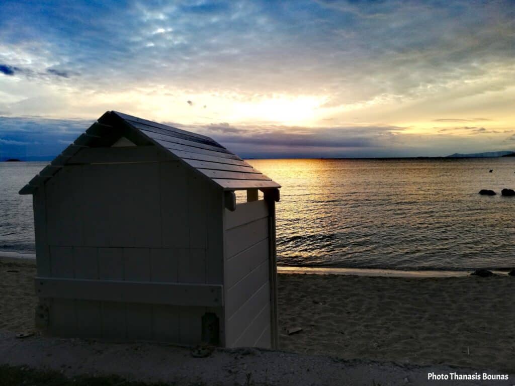 Sunset on a quiet beach in Greece with a wooden cabin and calm sea