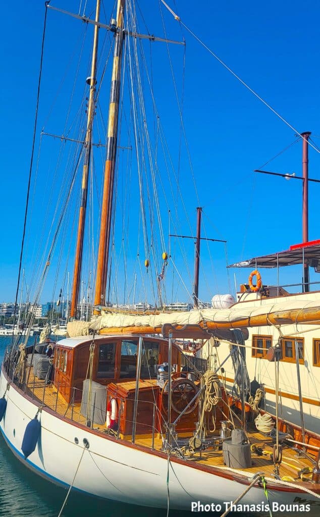 Classic wooden sailing yacht docked in marina under clear blue sky symbolizing arrival in sailing