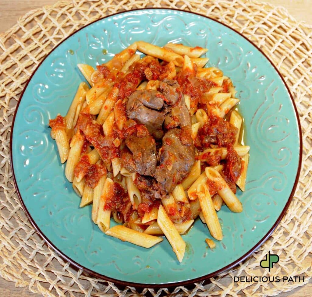 Plate of penne pasta with chicken livers in tomato sauce symbolizing Becoming, transformation through food, and the psychology of travel and Sailing.