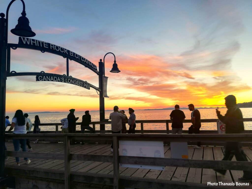 White Rock Pier at sunset with people walking and colorful sky in British Columbia