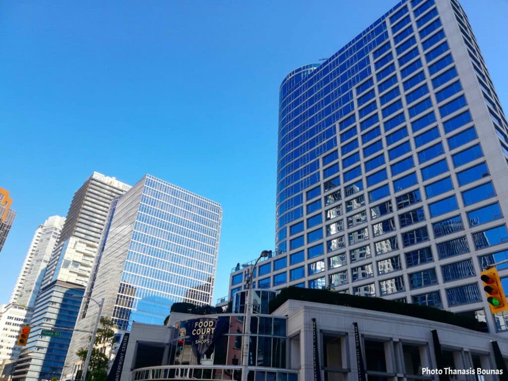 Downtown Vancouver modern glass buildings on a sunny day with blue sky reflections