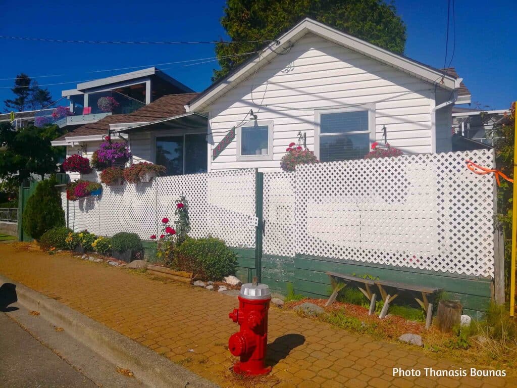 White residential house with flower baskets and lattice fence on a sunny street in White Rock British Columbia Canada
