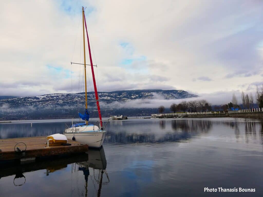 Sailboat at dock on Okanagan Lake Kelowna British Columbia Canada with snowy mountains
