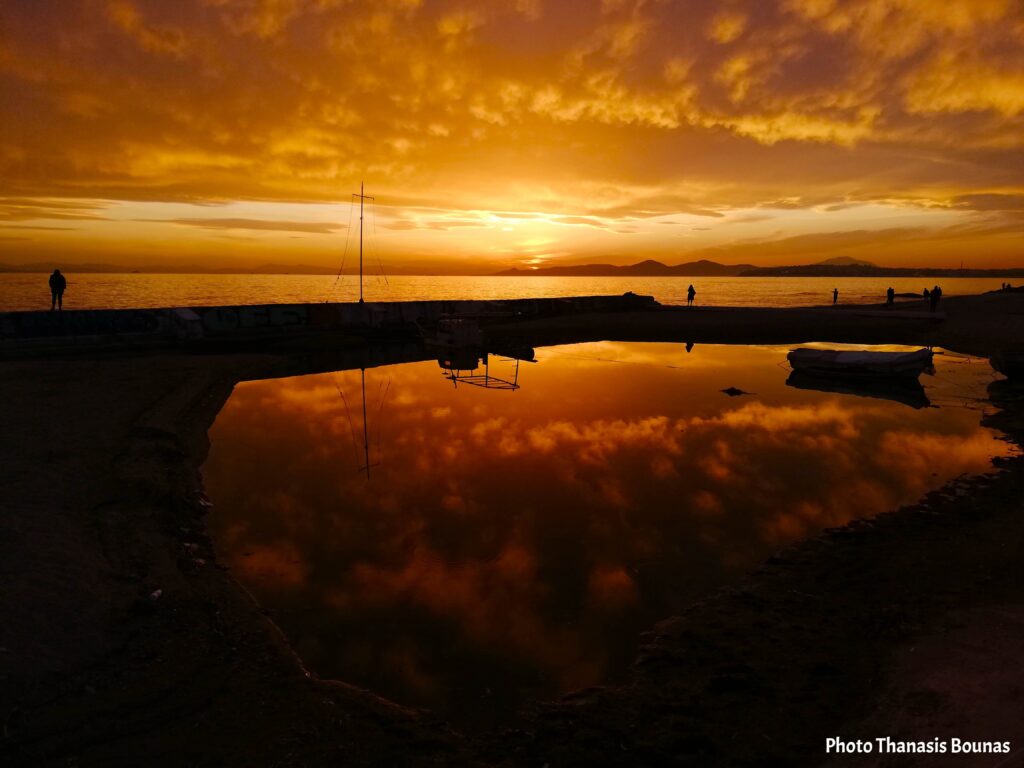 Sunset in Faliro Athens with reflections on water and silhouettes by the sea