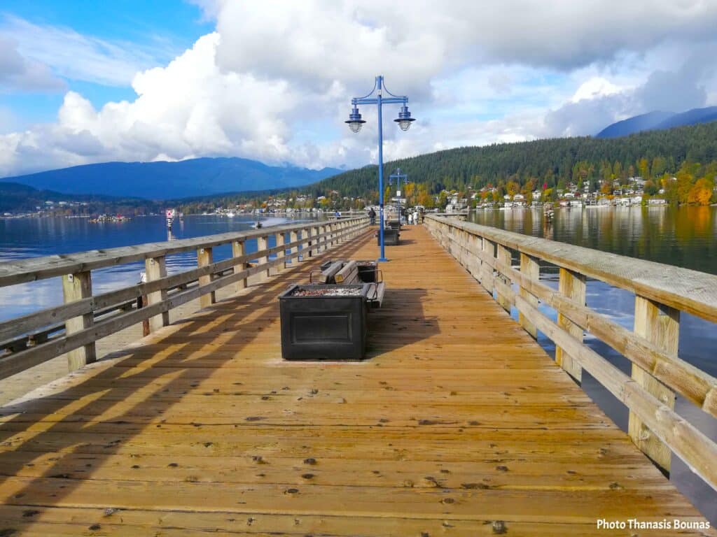 Port Moody pier wooden walkway with mountains and calm water in Vancouver area