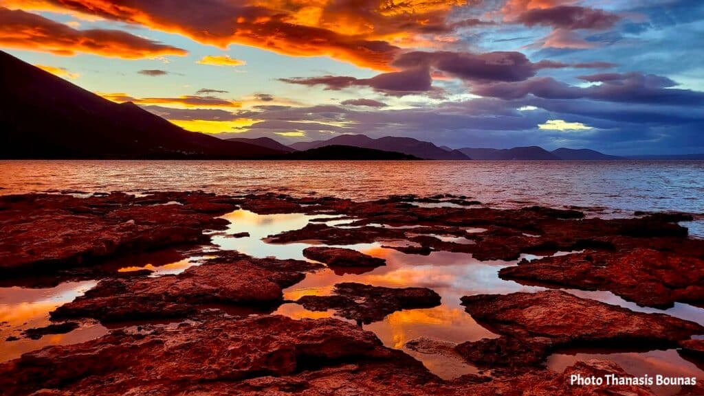 Alykes Beach Drosia Chalkida sunset with dramatic red sky and reflections on rocks Greece