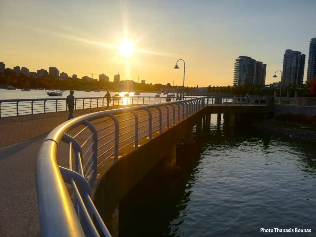 False Creek Vancouver waterfront walkway at sunset with city skyline and reflections