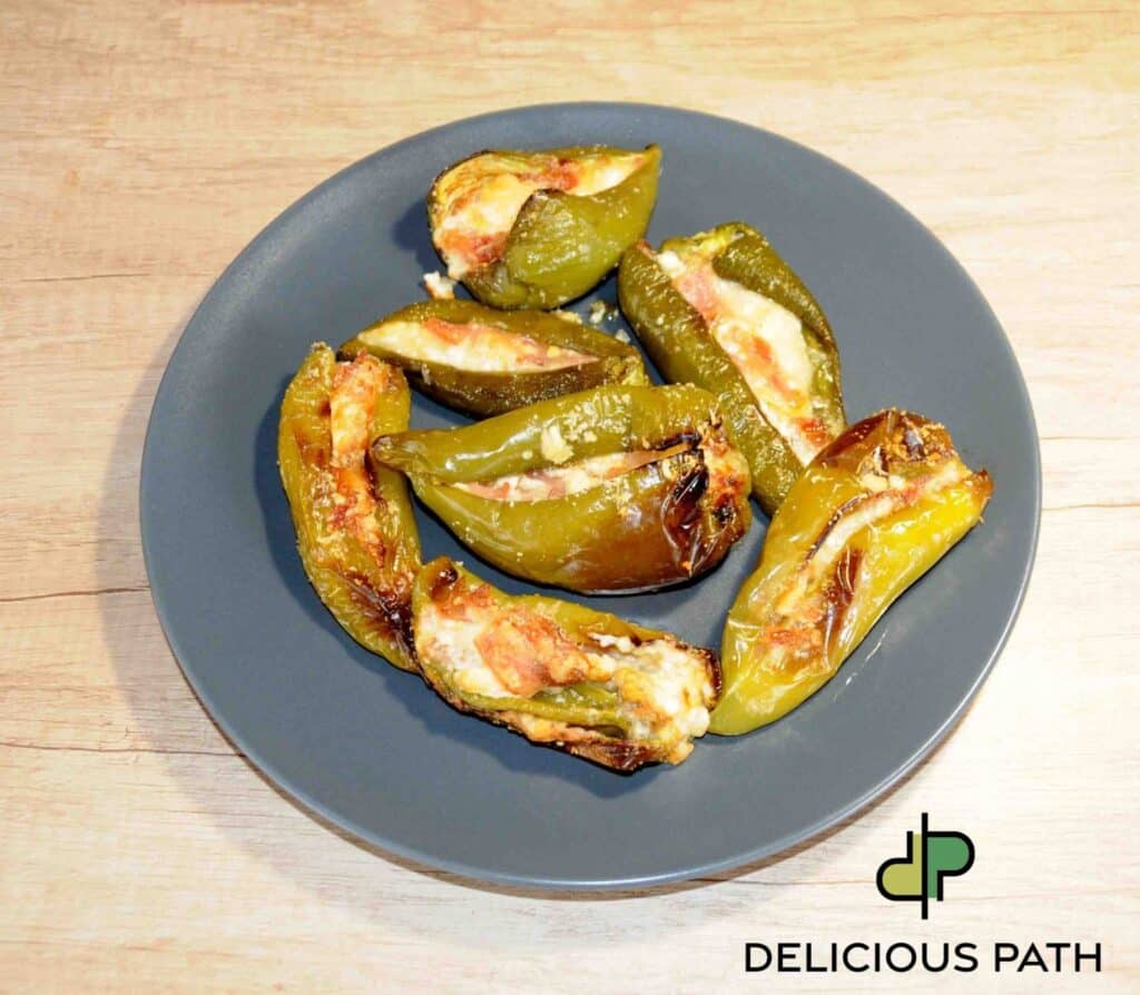 Oven baked stuffed green peppers with melted cheese on a grey plate symbolizing return, simplicity and sailing-inspired food philosophy.