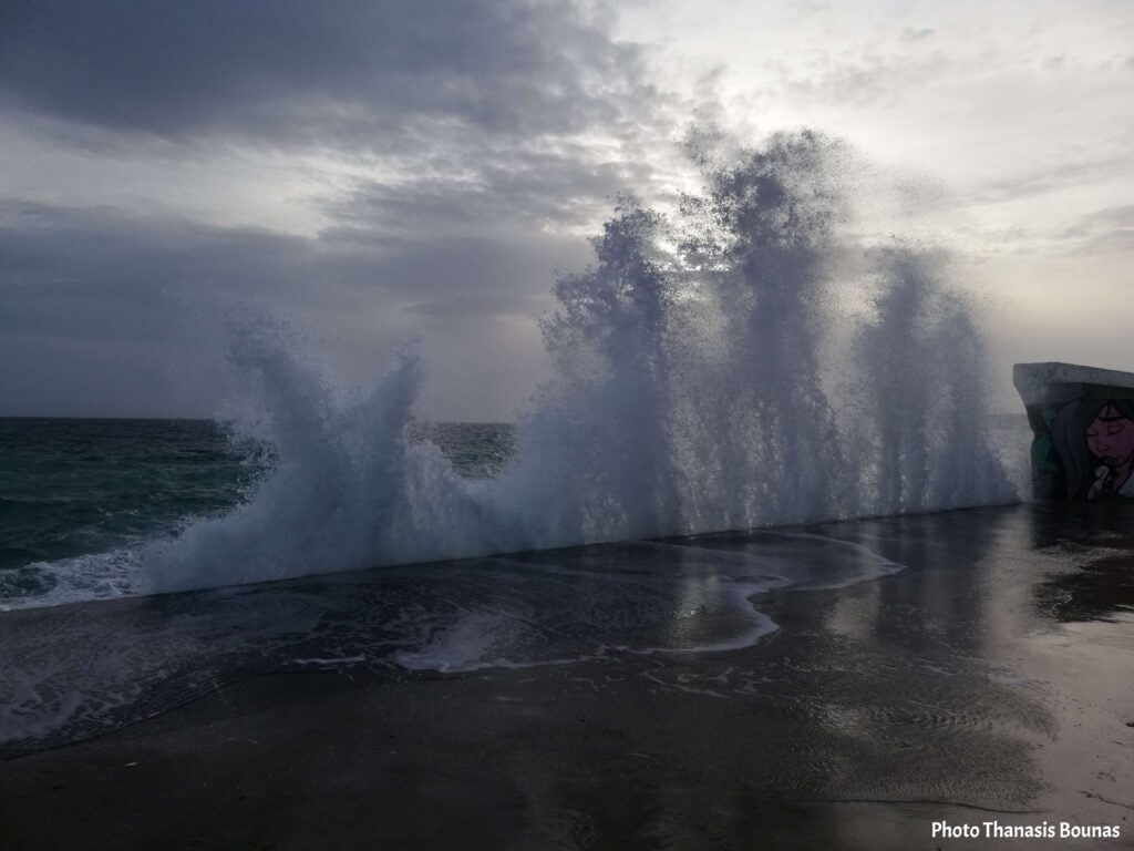 Powerful winter waves crashing on a seaside promenade in Greece under cloudy sky