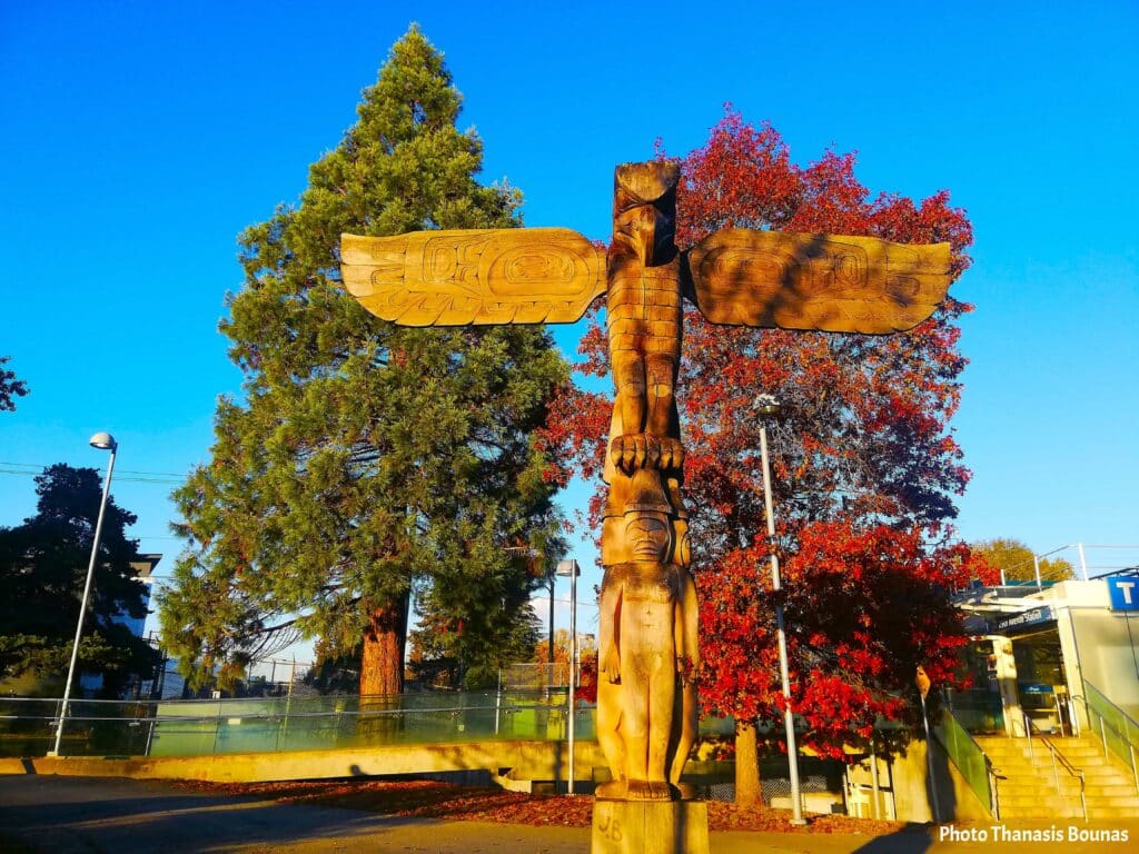 Wooden totem pole surrounded by autumn trees reflecting travel memory and Indigenous heritage