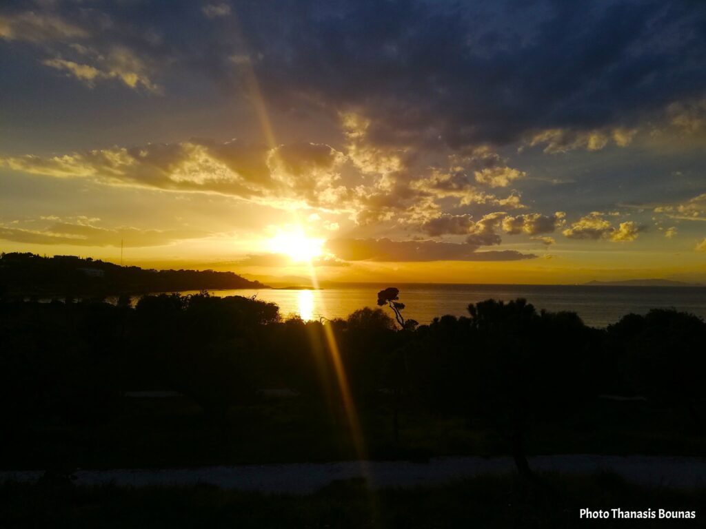 Romantic sunset in Greece with golden light over the sea and dramatic clouds
