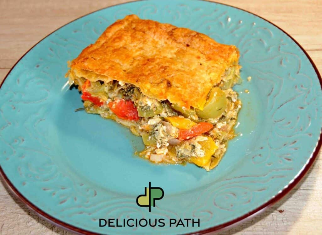 Slice of vegetable and cheese puff pastry pie on a turquoise plate