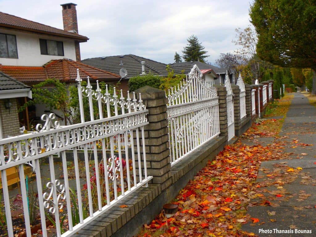 Quiet residential street with white fence and autumn leaves reflecting slow travel and neighborhood exploration
