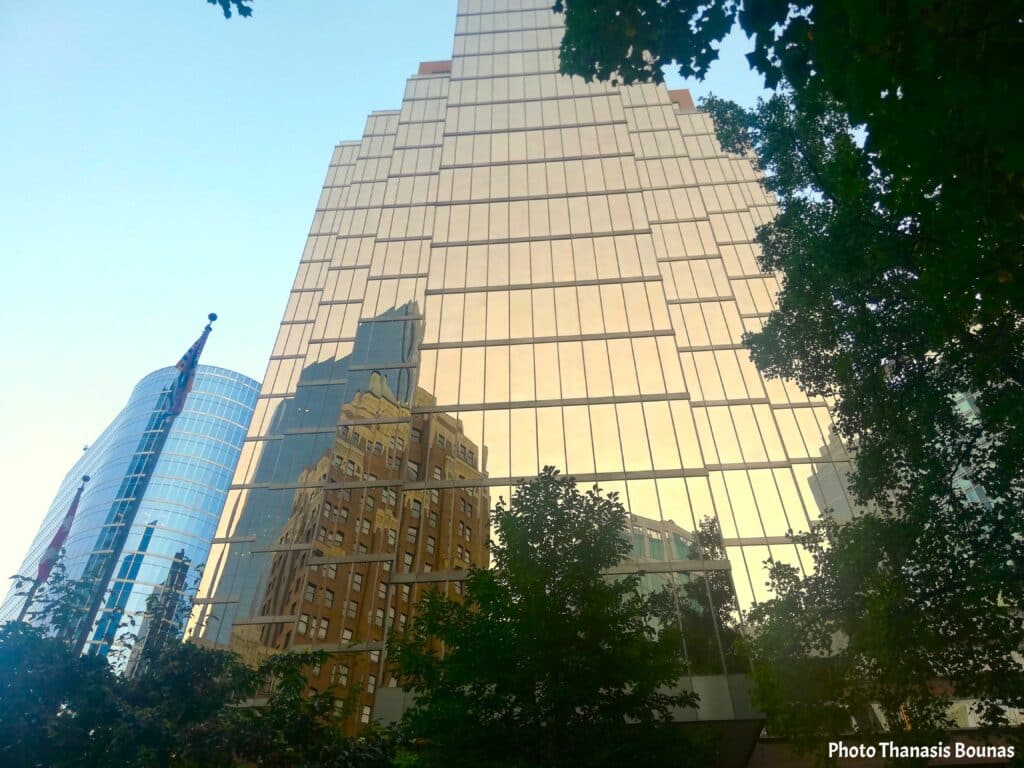 Downtown Vancouver skyscraper with glass reflections of buildings and trees under clear sky