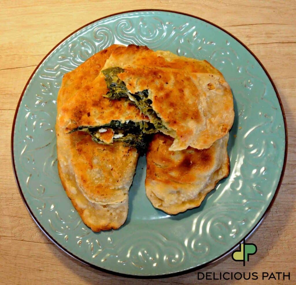 Homemade stuffed flatbread with spinach and cheese on a turquoise plate