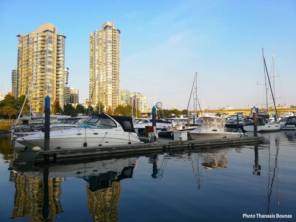 Boats and sailboats at Yaletown marina with Vancouver skyline reflections on calm water