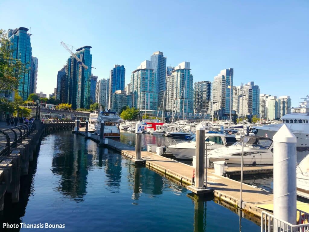 Boats resting in the marina along the Vancouver Seawall with the city skyline behind