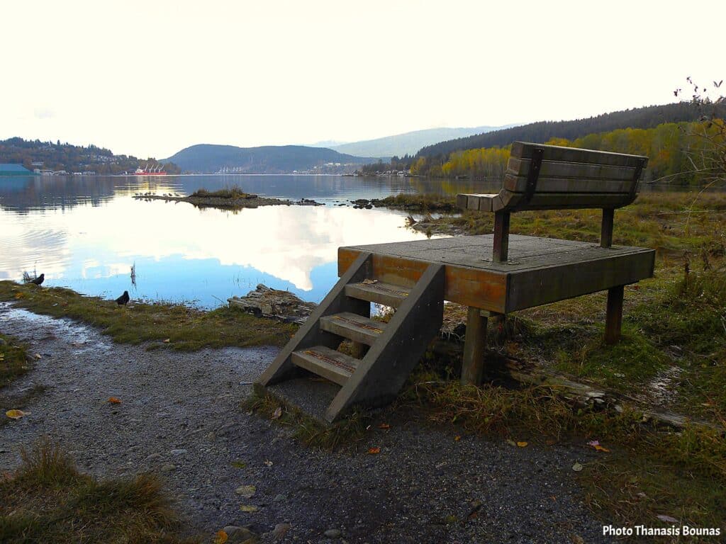 Wooden bench overlooking calm lake and mountains in Canada during a quiet travel moment