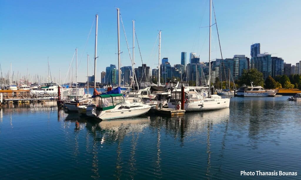 Sailing boats resting in a marina with the Vancouver skyline in the background