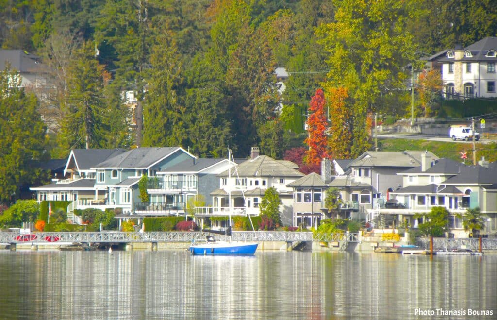 Waterfront homes with sailboats docked beside houses in a quiet Canadian coastal village during travel exploration