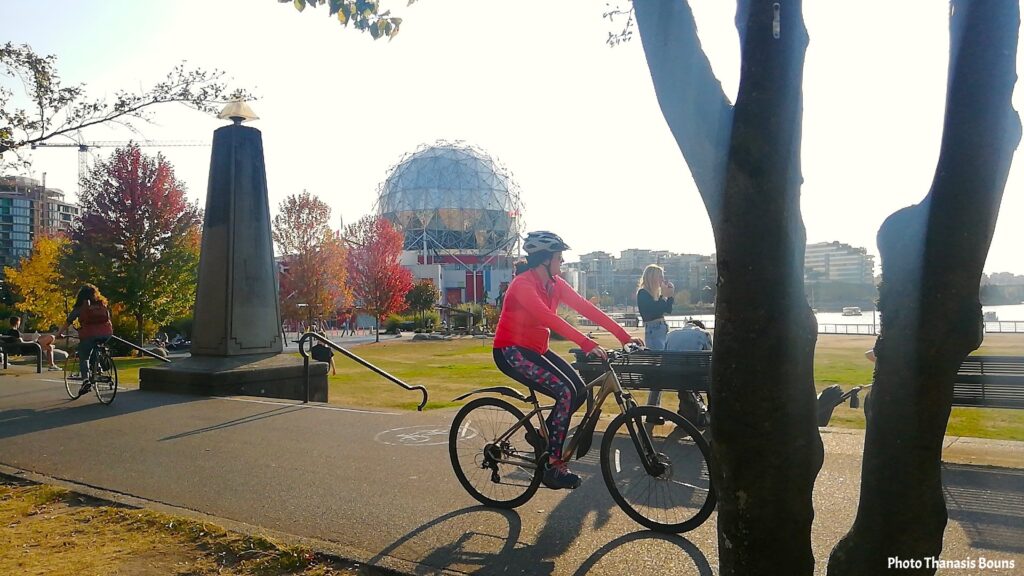 Cyclist riding along the waterfront path near Science World at False Creek in Vancouver