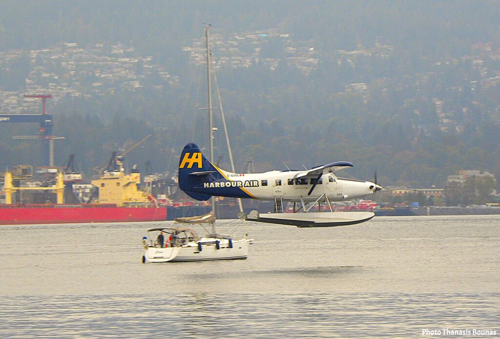 Harbour Air seaplane flying above a sailboat in Vancouver harbor during a reflective travel moment